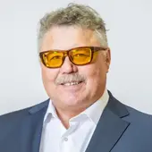 Alfred Scheuer, Mitglied des erweiterten Vorstands, in blaugrauem Anzug vor hellgrauem Hintergrund