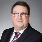 Tobias Michl, Mitglied des erweiterten Vorstands, im schwarzen Anzug vor grauem Hintergrund